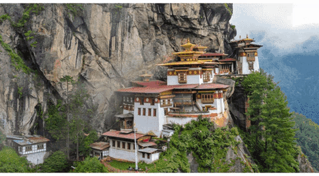a large building sits on top of a cliff in the mountains
