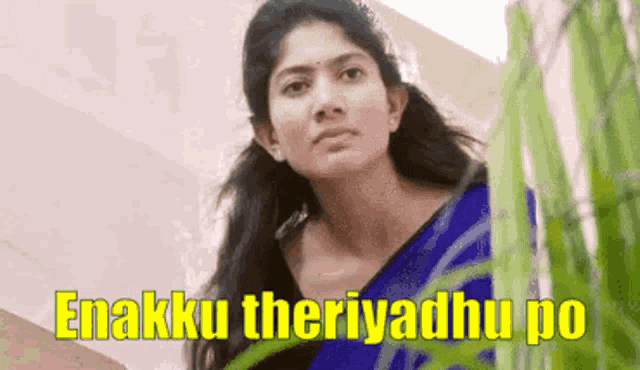 a woman in a blue saree is standing next to a plant with the words enakku theriyadhu po written above her .