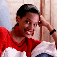 a woman in a red shirt is smiling with her hand on her forehead