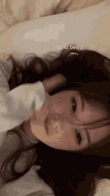 a girl is laying on a bed with the words go to bed written above her