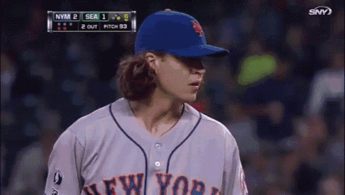 a baseball player for the new york mets stands in front of the scoreboard