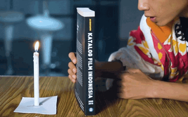 a person holding a book that says katalog film indonesia on it