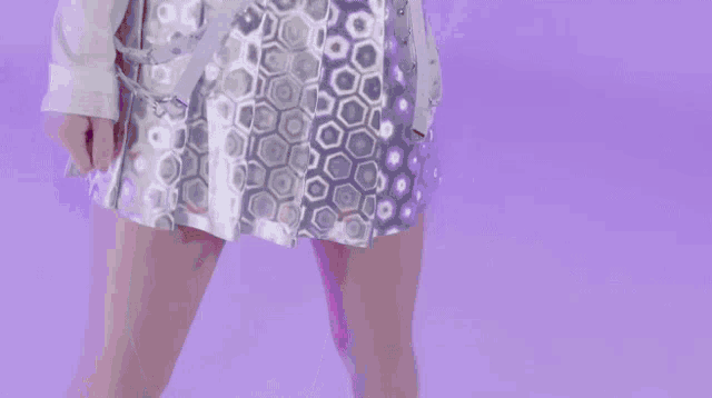 a woman in a white shirt is standing in front of a purple wall