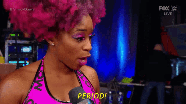 a woman with pink hair and a microphone says period