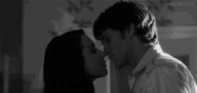 a man and a woman are kissing in a room in a black and white photo .