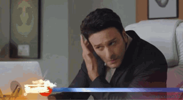 a man sitting in front of a laptop talking on the phone