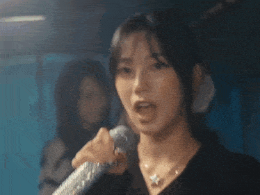a woman is singing into a microphone with rising written on the bottom right