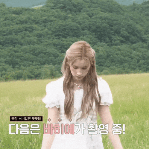a woman in a white dress is standing in a field with foreign writing
