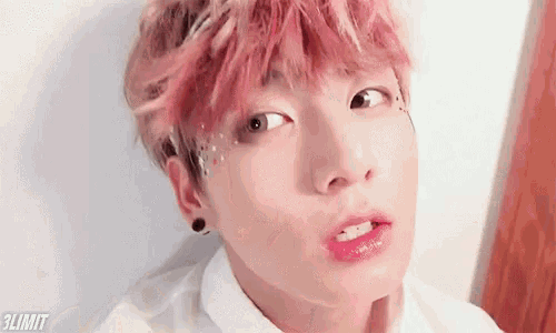 a close up of a person with pink hair and earrings .