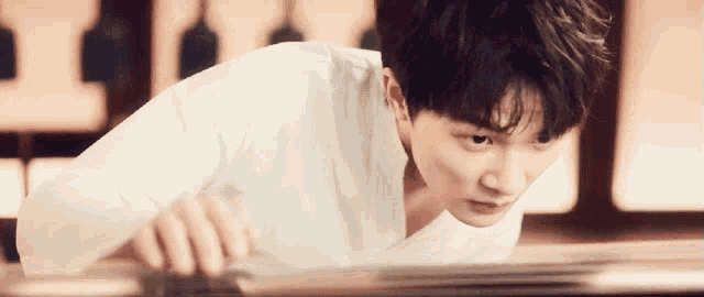 a young man in a white shirt is playing a piano