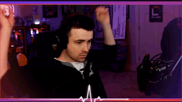 a man wearing headphones is sitting in a chair with his hands in the air