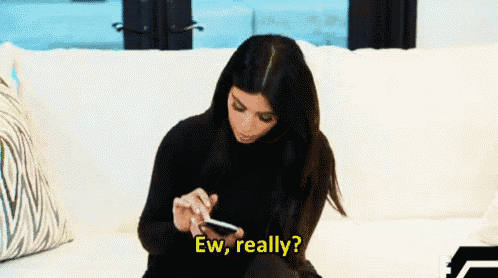 a woman is sitting on a couch looking at her cell phone and saying ew , really ?