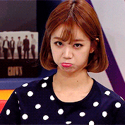 a woman with short hair is wearing a polka dot shirt and making a funny face .