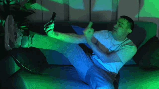 a man laying on a couch with his feet up and holding a cell phone
