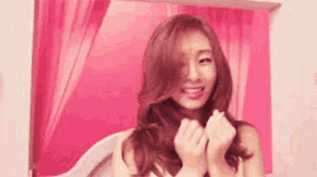 a woman is smiling and making a heart shape with her hands .