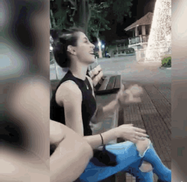 a woman sitting on a bench laughing with a man