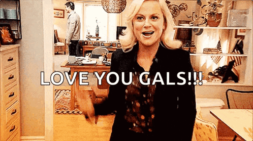 a woman is standing in a room with the words `` love you gals '' written on it .