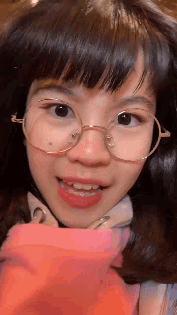 a close up of a young girl wearing glasses and a pink shirt