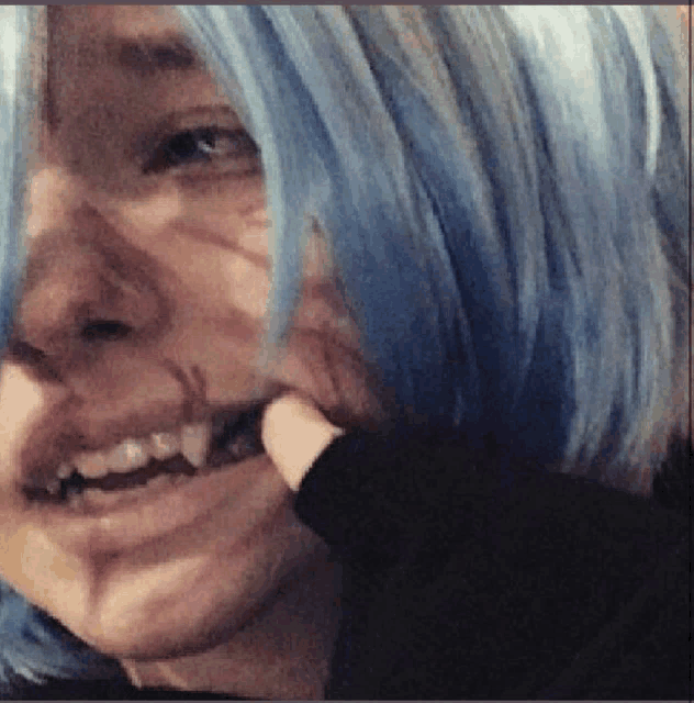 a close up of a person 's face with blue hair and fangs