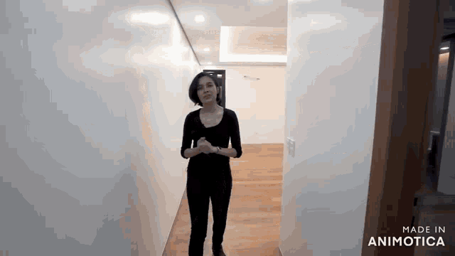 a woman is standing in a hallway with the words made in animatica on the bottom .
