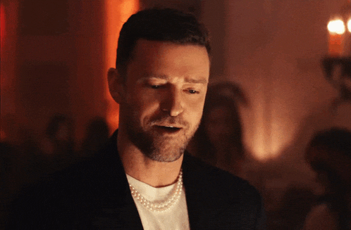 a man is wearing a pearl necklace and a black jacket