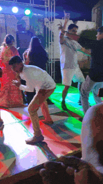 a group of people are dancing on a stage with green lights behind them
