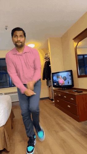 a man in a pink shirt is dancing in a room