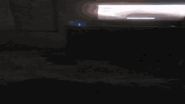a person is standing in a dark room with a light shining through a window