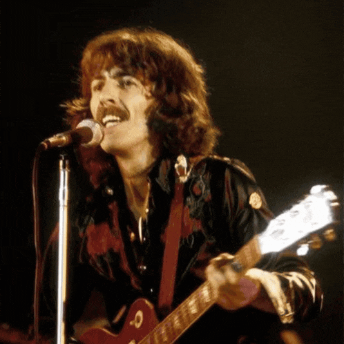 a man is singing into a microphone while holding a guitar