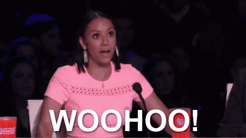 a woman in a pink shirt is sitting in front of a microphone and says woohoo .