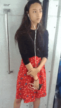 a woman wearing headphones stands in front of a door that says " please hold "