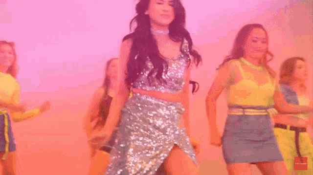 a woman in a sequined dress is dancing with a group of other women