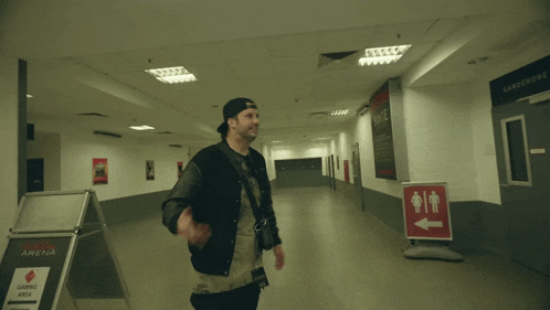 a man stands in a hallway with a rena sign in the foreground