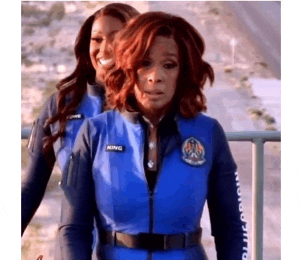two women are standing next to each other wearing blue jumpsuits .