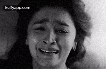 a woman is crying with her eyes closed in a black and white photo .