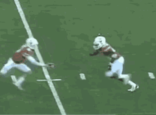 a football player in a red jersey is being tackled by another player in a white jersey