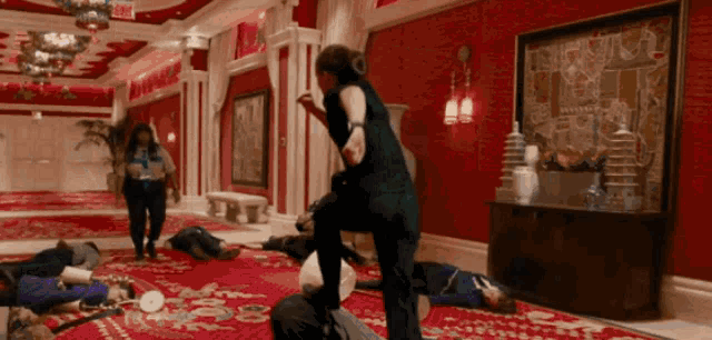 a woman is kicking a man in the face in a hallway with an exit sign in the background