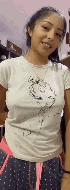 a woman is wearing a white t-shirt with a drawing of a girl on it .