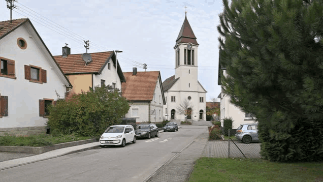 a white car is parked on the side of the road next to a church