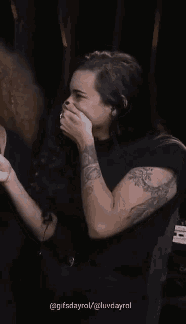 a woman with a tattoo on her arm is covering her face with her hand