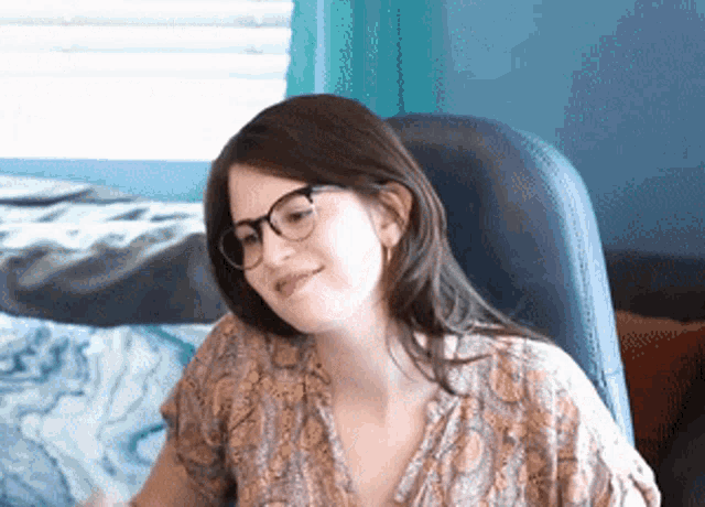 a woman wearing glasses is sitting in a chair and smiling