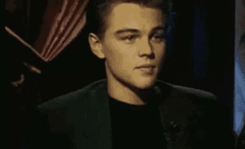 a close up of a man in a suit and black shirt looking at the camera .