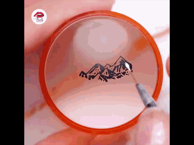 a person is painting a picture of mountains on a circle with a magnifying glass