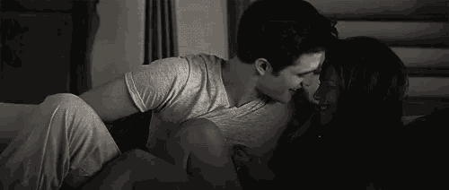 a man and a woman are laying on a bed and kissing .