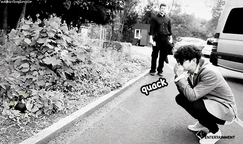 a black and white photo of a man squatting on the side of the road with the word quack written on it