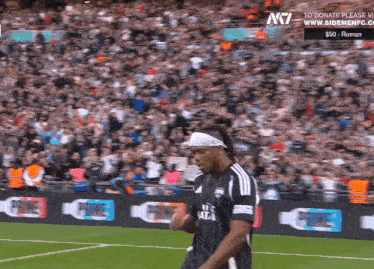 a soccer player wearing a headband stands on a field in front of a crowd