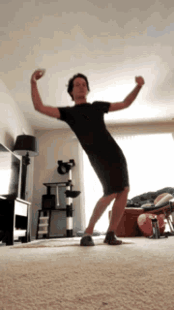 a man is dancing in a living room with his arms in the air