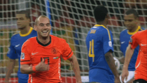 a soccer player wearing an orange jersey with the number 13