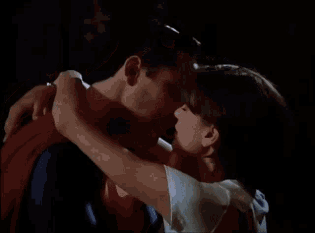 a man and woman are kissing in a dark room