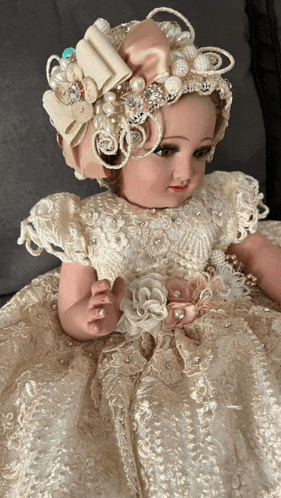 a doll wearing a white dress with pearls and a headband